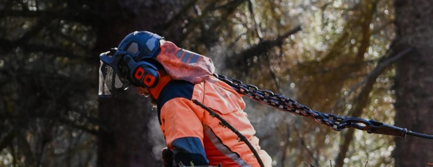 A forestry worker in protective clothing carrying a choker chain